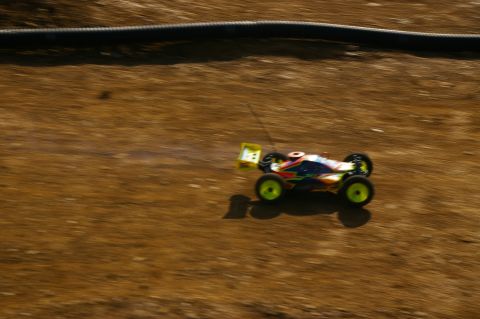 1986 Ford Bronco - A colorful remote control buggy races across a dirt track, kicking up dust.