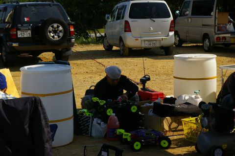 1986 Ford Bronco - Several vehicles are parked on a dirt lot, with people gathered around RC cars and equipment.