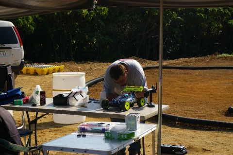 1986 Ford Bronco - A person works on a remote control car at a table, with a white van visible in the background.