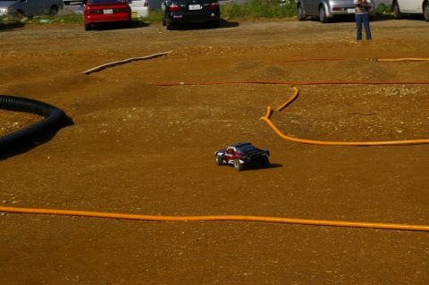 1986 Ford Bronco - A remote control car navigates a dirt track with orange hoses marking the course.