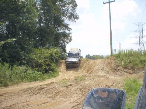1983 Ford Bronco - Truck navigates a challenging muddy incline on an off-road trail.