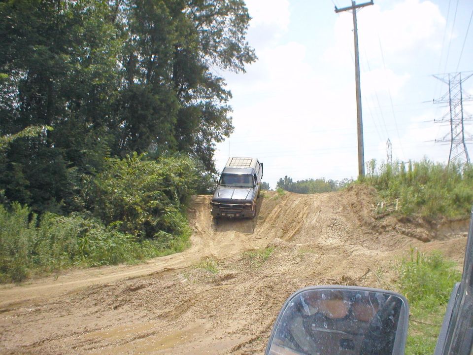 Dark SUV descending a muddy dirt trail under power lines