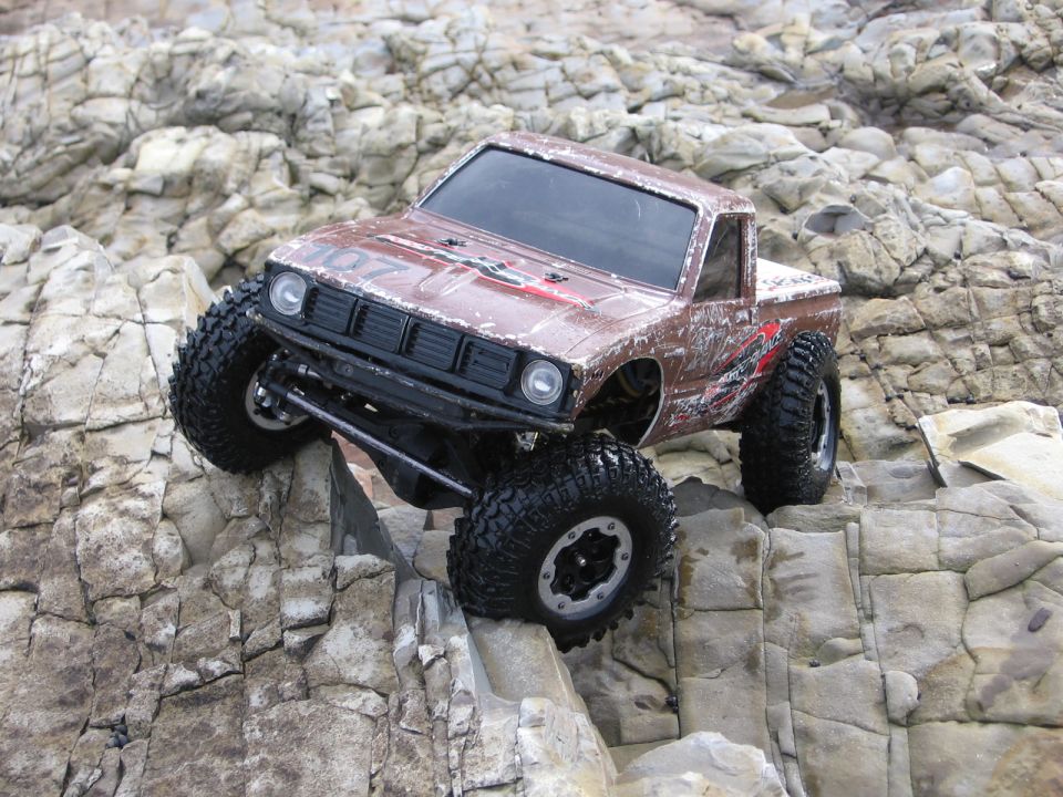 Brown remote control rock crawler truck with large tires climbing over rocks