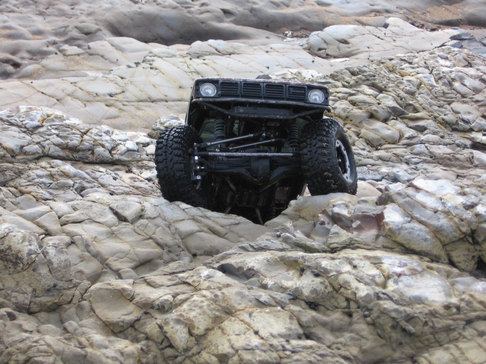 Black off-road vehicle with large tires climbing over rocks