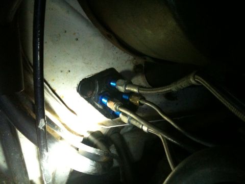 1989 Ford Bronco - Close-up view of brake line fittings with blue anodized connectors, likely an aftermarket modification.