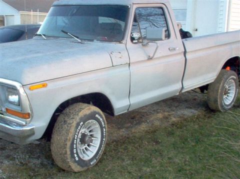 1996 Ford Bronco - A light-colored Ford pickup truck is parked on a grassy area, showing its side and front quarter view.