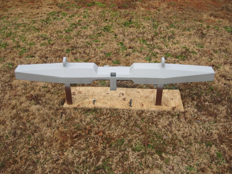 Gray aftermarket truck bumper with tow hooks, mounted on plywood