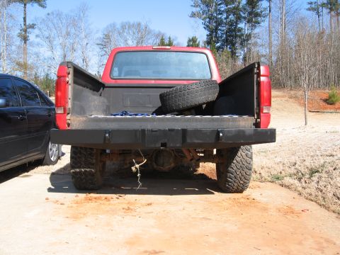 1995 Ford F-150 - The rear bumper of a red pickup truck is visible, with a spare tire stored in the bed. The truck appears to be a 1995 Ford F-150.