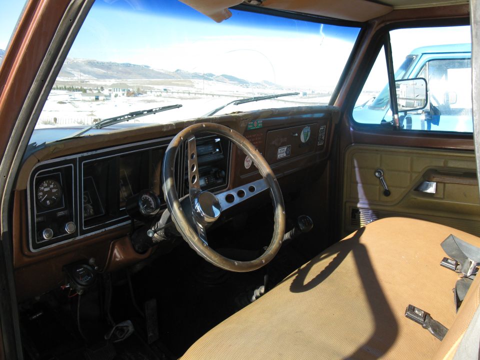 1977 Ford F-250 interior, brown dashboard, aftermarket steering wheel, tan seat, view of another truck through windshield