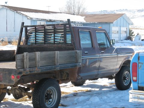 1977 Ford F-250 - A brown crew cab pickup truck with a flatbed sits in the snow next to another vehicle.