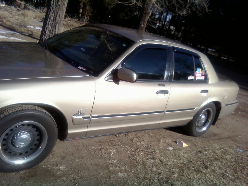2000 Mercury Grand Marquis, tan, side view, parked on dirt with trees in background
