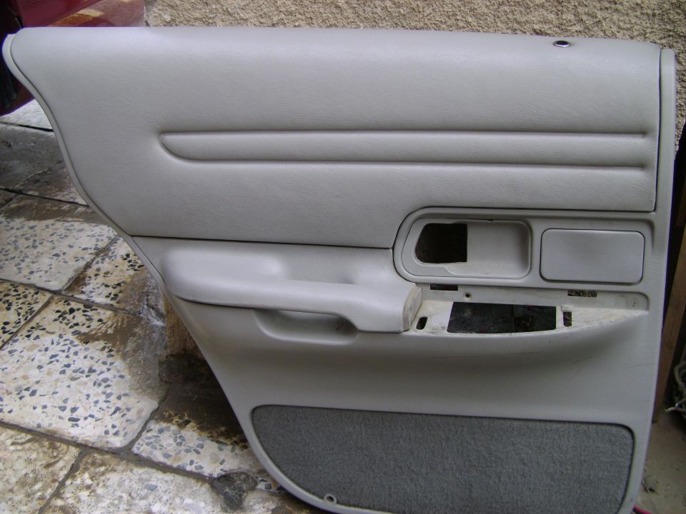 Light gray interior door panel with speaker grille and handle cutout