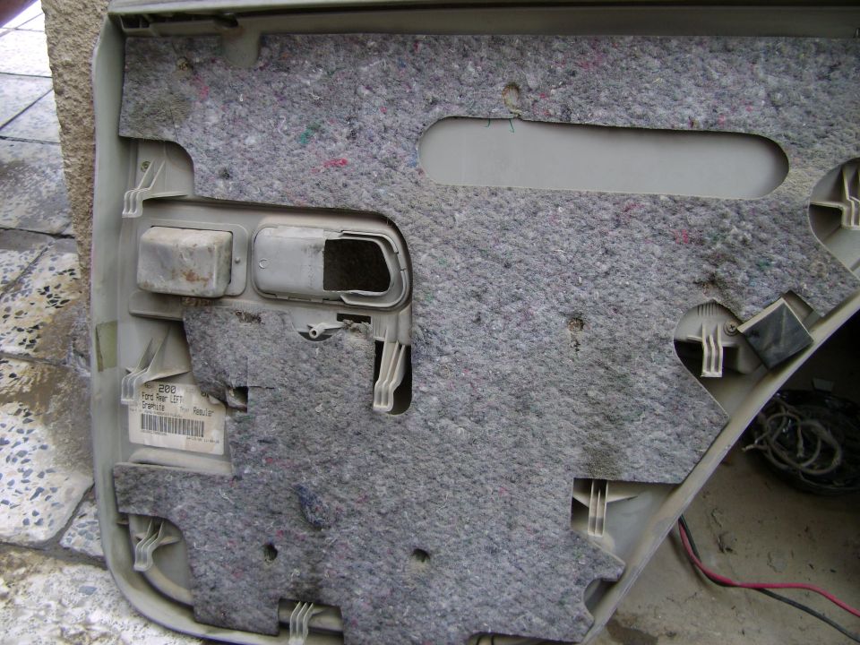 Interior of a car door panel with insulation, showing a label with '2000 Ford Rear Left' visible