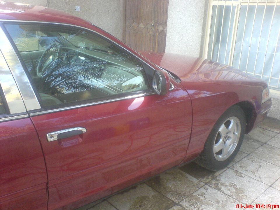 Red 1998 Ford Crown Victoria sedan, side view, chrome trim, alloy wheels, parked outdoors