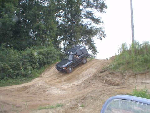1983 Ford Bronco - A black SUV navigates a steep dirt incline, with another vehicle partially visible in the foreground.