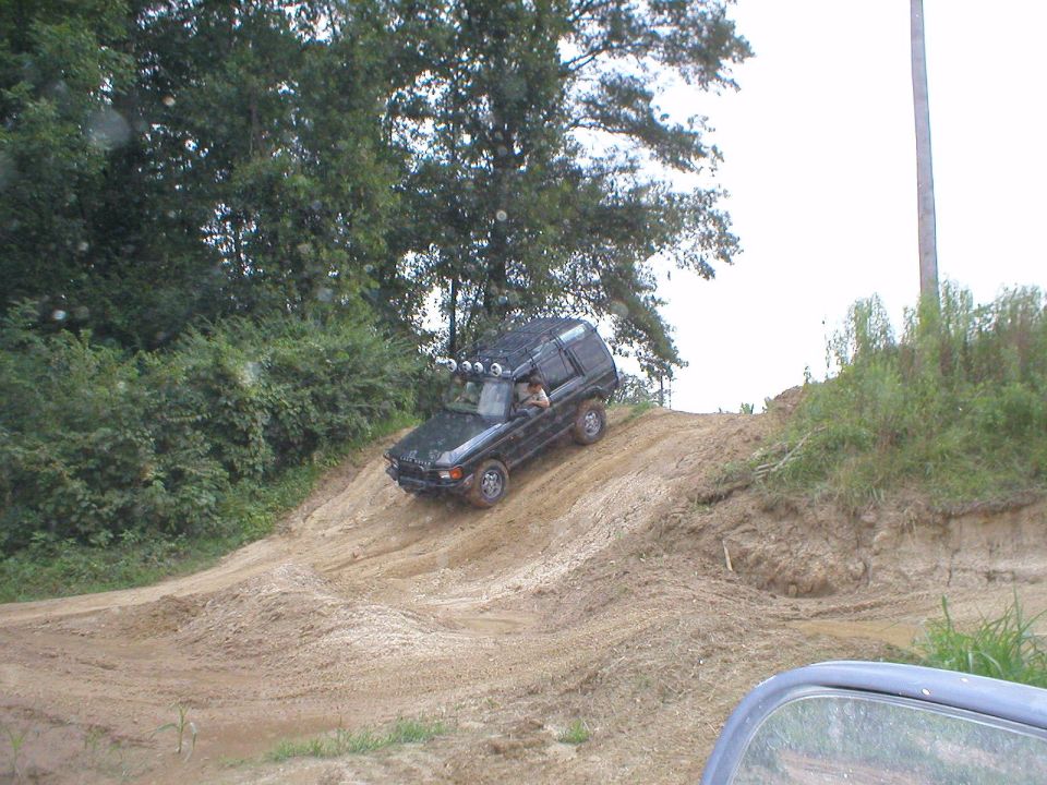 Dark SUV with roof lights descending a steep dirt hill off-road