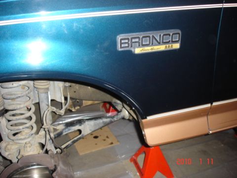 1995 Ford Bronco - Close-up of a teal and tan Ford Bronco Eddie Bauer showing the fender and lower body panel with suspension components.
