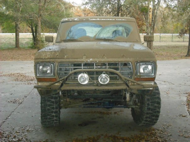 Mud-covered 1979 Ford Bronco front view with aftermarket bumper and lights