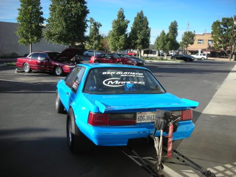 1992 Ford Crown Victoria - A bright blue drag car is parked with its rear facing the camera, displaying racing decals on the rear window and a California license plat…
