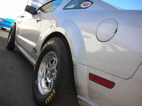 1992 Ford Crown Victoria - A silver Ford Mustang with racing tires is parked next to a blue car.