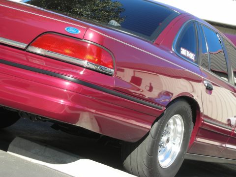 1992 Ford Crown Victoria - A red Ford Crown Victoria is shown from the rear quarter panel, chrome wheels and drag tires.