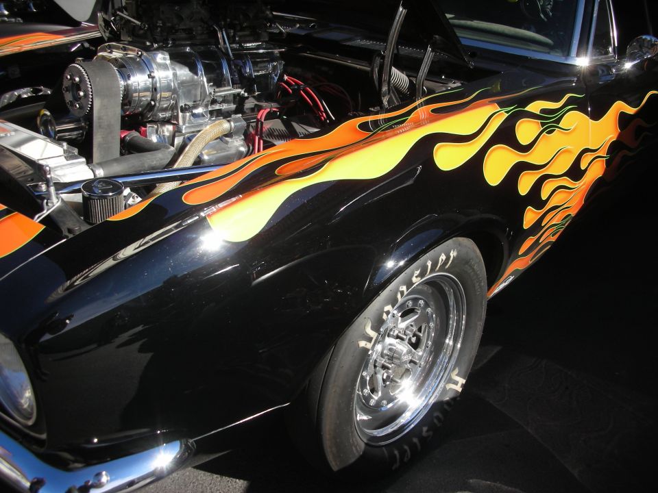 Black hot rod with orange and yellow flame graphics on the fender and hood. Supercharger visible in engine bay