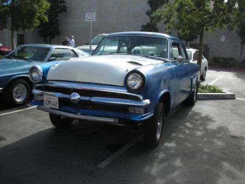1992 Ford Crown Victoria - A vintage blue and white sedan parked in a lot, with another car to its left.
