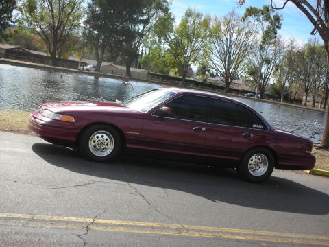 1992 Ford Crown Victoria - A maroon 1992 Ford Crown Victoria sedan is parked by a lake on a sunny day.