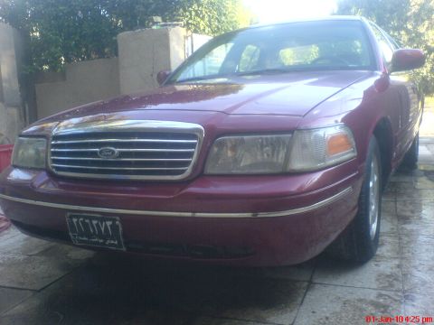 1998 Ford Crown Victoria - Maroon 1998 Ford Crown Victoria parked outside, showing its front grille and headlights.