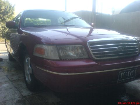 1998 Ford Crown Victoria - The front of a maroon 1998 Ford Crown Victoria is visible from a 3/4 angle.