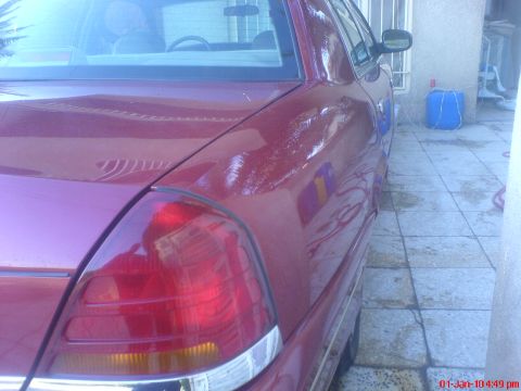 1998 Ford Crown Victoria - Rear view of a red 1998 Ford Crown Victoria, showing the quarter panel and taillight detail.
