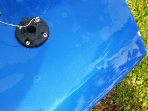 1986 Ford Bronco - Close-up of a blue vehicle's body panel a black fuel filler cap with a tether.