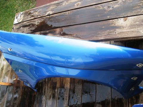 1986 Ford Bronco - A blue car fender is shown resting on wet wooden planks.