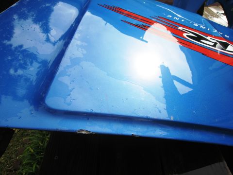 1986 Ford Bronco - Close-up of a blue automotive part racing decals and water droplets.