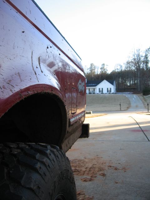 1995 Ford F-150 - Mud-covered 1995 Ford F-150 rear quarter panel and tire parked on a driveway.