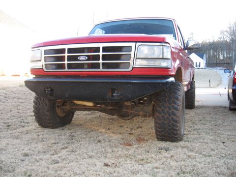 1995 Ford F-150 - Front view of a red Ford truck with an aftermarket bumper and lifted suspension.