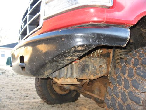 1995 Ford F-150 - Close-up view of the front bumper and tire of a red 1995 Ford F-150.