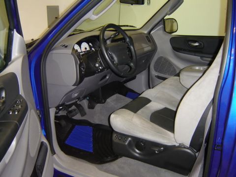 2007 Ford Mustang - The interior of a blue pickup truck is shown, the driver's side controls and seating.