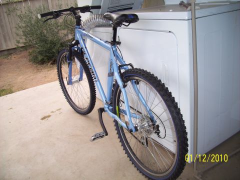 1993 Ford Probe - A light blue bicycle is parked next to a white appliance, possibly a dryer, on a concrete patio.