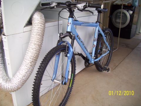 1993 Ford Probe - Blue mountain bike with front suspension parked next to a washing machine.