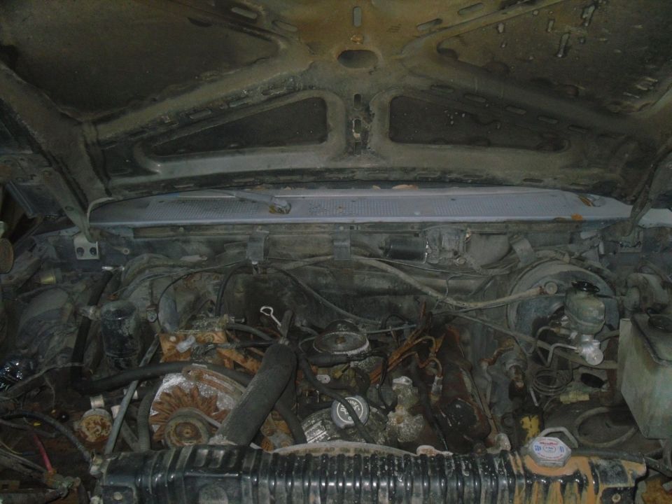 Engine bay of an older truck, showing engine components, wiring, and radiator