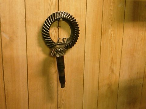 2002 Chevrolet Camaro - Ring and pinion gear set with 'LS' marking, likely for a differential, mounted on a wood-paneled wall.