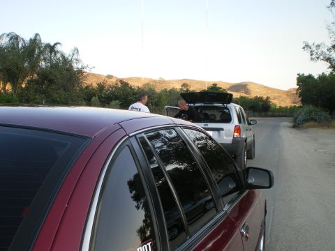 1992 Ford Crown Victoria - Roofline and rear side glass of a maroon four-door sedan with heavily tinted windows, shot from behind the driver's shoulder on a rural roa…