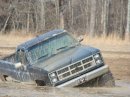 1979 Ford Bronco - Pickup truck stuck in mud, likely from the 1980s based on grille design.