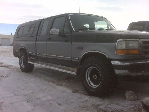 1994 Ford F-150 - This two-tone 1994 Ford F-150 pickup truck is equipped with a camper shell and seen in a snowy environment.