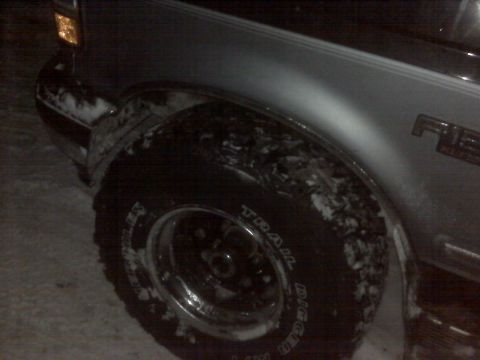 1994 Ford F-150 - Close-up of a 1994 Ford F-150 fender and tire, with snow visible on the vehicle.