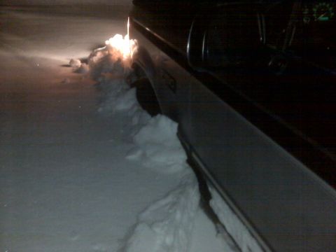 1994 Ford F-150 - A truck is stuck in a snowdrift, with its headlights illuminating the snow it's pushing.