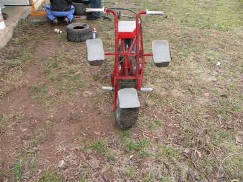 1901 Ford Bronco - A red three-wheeled mini-bike sits in a grassy yard, appearing to be a project in progress.