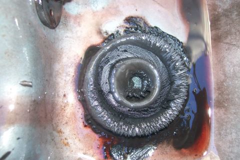 1992 Ford C-350 (Centurion Conversions) - Close-up of a transmission drain plug showing significant wear and metal shavings, indicating potential internal damage.