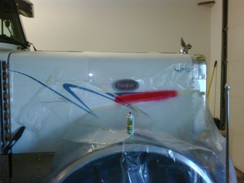 2003 Peterbilt 379 - A Peterbilt truck hood is covered in plastic sheeting and has red spray paint applied to it.